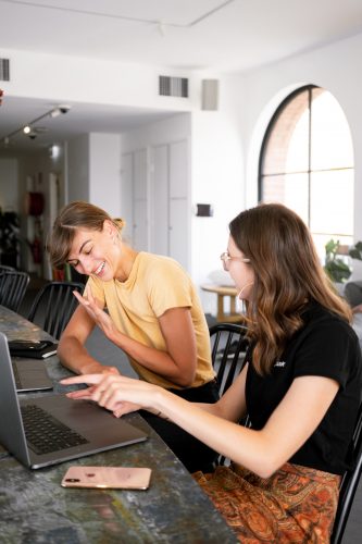 Pointing at a laptop, two people talking and discussing something.