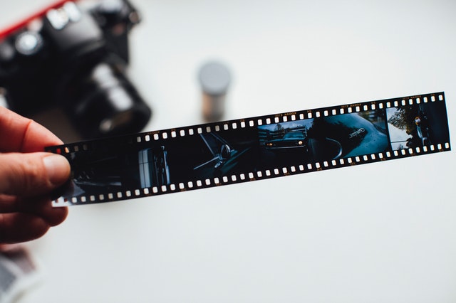 a person holding negatives of a filmstrip- portraying create images