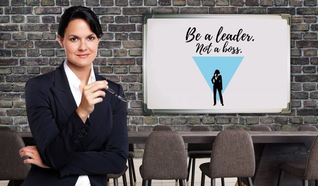 A lady standing in front of a board that states - be a leader not a boss
