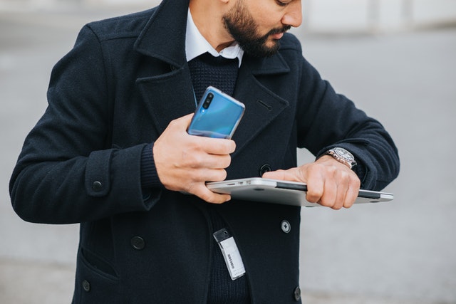 a man holding a laptop is staring at his watch, which depcits the importance of time-management